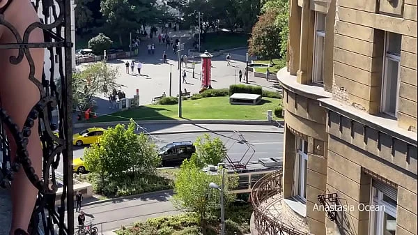 A woman undresses on a balcony in the city center. Public flashing.